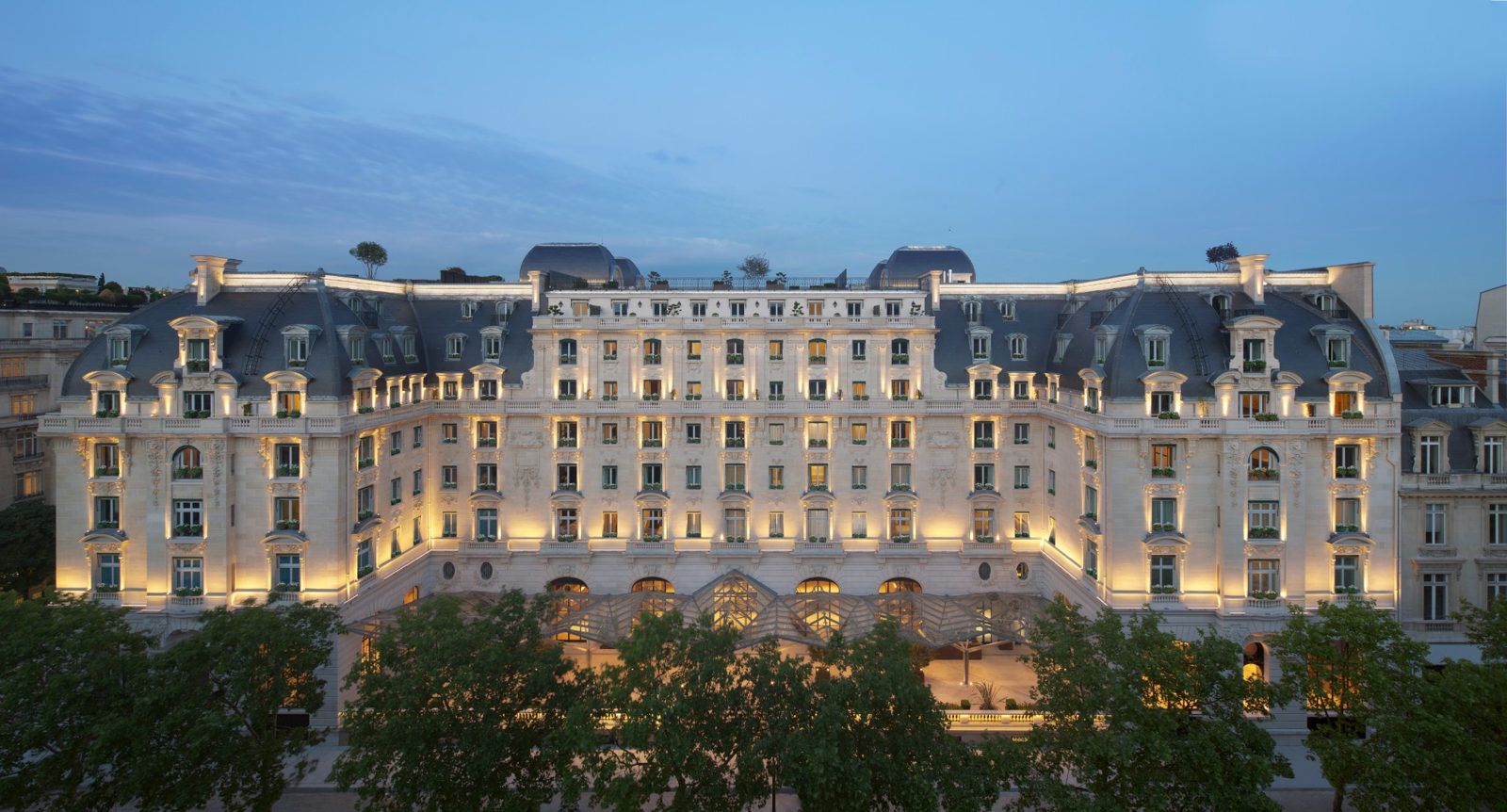 Fachada iluminada de The Peninsula Paris al anochecer